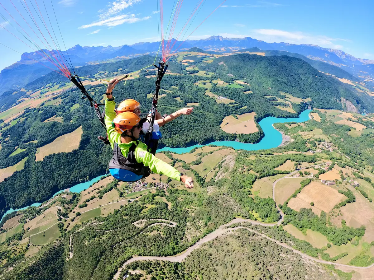Vol en parapente biplace au-dessus des eaux turquoise du lac de Monteynard depuis le Sénépy